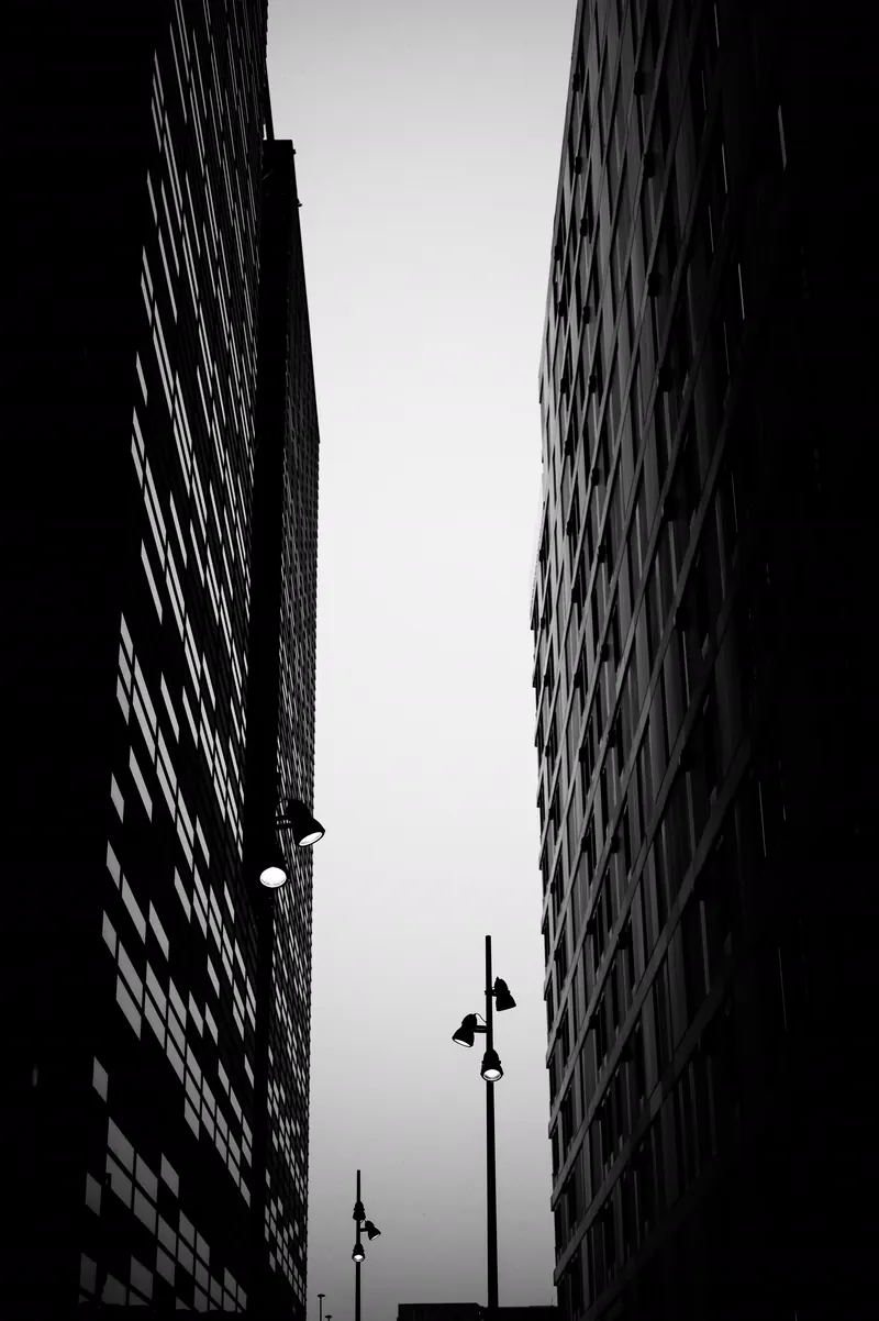 Faixa de céu claro entre duas torres escuras, com postes na base.